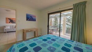 Relax in a stylish room with a large bed, nightstand, and sliding door leading to a patio with a scenic view.