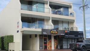 A two-story building with a 'Pilot Station Pizza' sign, a 'Hooker' sign, and a 'Holiday Accommodation' sign.