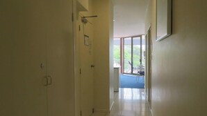 A hallway leading to a balcony with a view of greenery.
