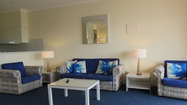 A living room with a blue sofa, two plaid armchairs, a coffee table, and two lamps.