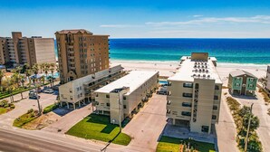 A coastal hotel with multiple buildings, a parking lot, and a beach view. - Beachfront condo with multiple beach views (Gulf Shores)