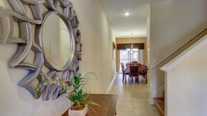 A hallway with a wooden bench, a potted plant, and a wall-mounted mirror. - Your new vacation home at Paradise Palms Resort? (Kissimmee)