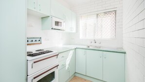 A compact kitchen with white appliances, a window with blinds, and light green cabinetry. - TRAVELLERS PALMS UNIT 1 - RECENTLY RENOVATED (SOUTH WEST ROCKS)