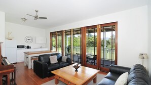 A spacious living area with a black leather sofa, a wooden coffee table, and a kitchen area with a microwave and cabinets.