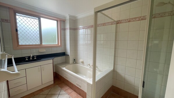 A bathroom with a bathtub, a shower, and a window.