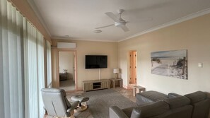 A living room with a ceiling fan, a flat-screen TV, a painting, and a sofa. - POINT BRINER 6 - MODERN FAMILY UNIT, GREAT VIEWS (South West Rocks)