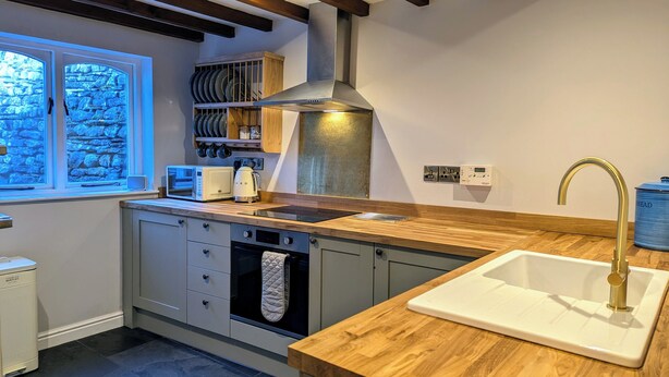 Une cuisine moderne dotée d’un plan de travail en bois, d’un four encastré et d’un évier en acier inoxydable.
