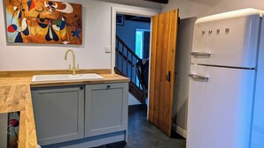 Une cuisine avec un réfrigérateur blanc, un plan de travail en bois et un évier.