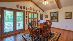 A dining area with a wooden table and chairs, a ceiling fan, and a large window with blinds. - The Perch - 3 BR, 3 BA One Level Home, Panoramic Long-Range Mountain View (Waynesville)