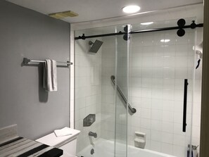 Een moderne badkamer met een glazen douchecabine, een witte wastafel en een handdoekrek.