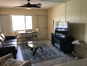 A living room with a sofa, a glass coffee table, a TV stand, and a dining area with chairs and a table. - Pirate's Paradise-don't have to walk the plank for this great harbor view!! (Punta Gorda)