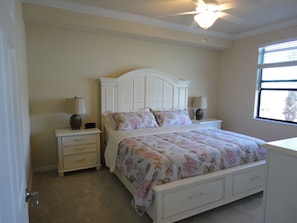 A bedroom with a bed, two bedside tables, a ceiling fan, and a window.