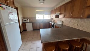A kitchen with wooden cabinets, a white refrigerator, a microwave, a dishwasher, a stove, and a window. - CARRINGTON TERRACE 4 - CLOSE TO FRONT CREEK BEACH ACCESS (South West Rocks)