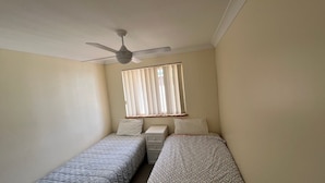 A bedroom with two single beds, a ceiling fan, a window with blinds, and a nightstand. - CARRINGTON TERRACE 4 - CLOSE TO FRONT CREEK BEACH ACCESS (South West Rocks)