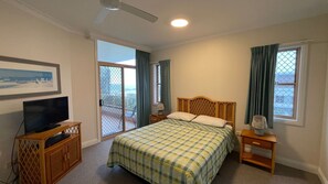 A bedroom with a bed, a television, a window with curtains, and a balcony. - POINT BRINER 4 - MAIN BEACH VIEWS, SINGLE LOCK UP GARAGE (South West Rocks)