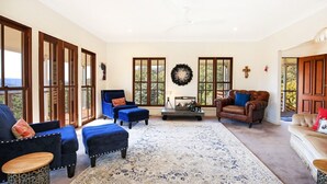 A spacious living room with large windows, a fireplace, and a cross on the wall.