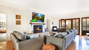 A living room with a fireplace, a large TV, and a sofa.