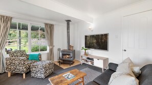 A cozy living room with a fireplace, a sofa, a coffee table, and a TV.