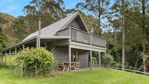 A two-story house with a balcony, surrounded by greenery. - Alcheringa Cottage - Amazing location with views! (KANGAROO VALLEY)