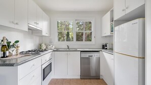 A modern kitchen with white cabinetry, a stainless steel dishwasher, and a built-in oven. - Alcheringa Cottage - Amazing location with views! (KANGAROO VALLEY)