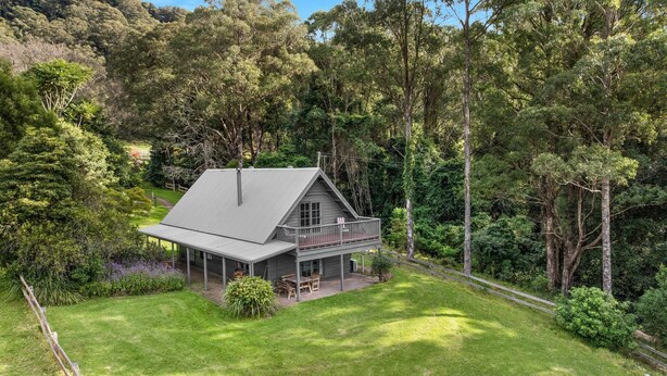 A two-story house with a balcony, surrounded by dense forest. - Alcheringa Cottage - Amazing location with views! (KANGAROO VALLEY)