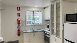A compact kitchen with a window, a fire extinguisher, and a microwave. - Little Ripple- Perfect couple retreat (South West Rocks)