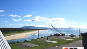 A coastal view with a beach, a crane, and vehicles. - Little Ripple- Perfect couple retreat (South West Rocks)
