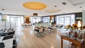 Un espace de restauration moderne, doté de tables et de chaises, d’un comptoir et d’une grande fenêtre laissant entrer la lumière naturelle.