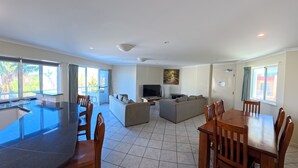 A spacious living area with a dining table, sofas, and a TV. - OCEANSHORES 18 LOVELY THREE BEDROOM UNIT CLOSE TO TOWN (SOUTH WEST ROCKS)