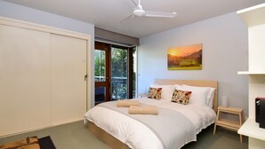 Une chambre à coucher avec un lit, un ventilateur de plafond, un tableau et une armoire.