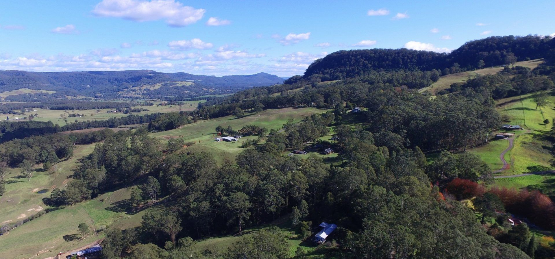 A rural landscape with a house surrounded by trees and open fields.