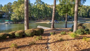 A lakeside path leading to a dock with boats, surrounded by trees and a clear sky.