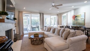 A spacious living room with a fireplace, a large sectional sofa, a round coffee table, and a dining area with a table and chairs.