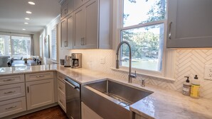 A modern kitchen with white cabinetry, a stainless steel sink, and a herringbone-patterned backsplash.