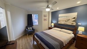 A bedroom with a bed, a chair, a desk, a ceiling fan, and a window with curtains. - OCEAN SHORES 16 - 50 METRES TO BEACH & POOL IN COMPLEX (South West Rocks)