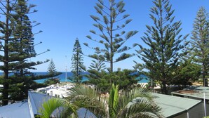 Ein Küstenresort mit Kiefern, blauem Himmel und Blick aufs Meer.
