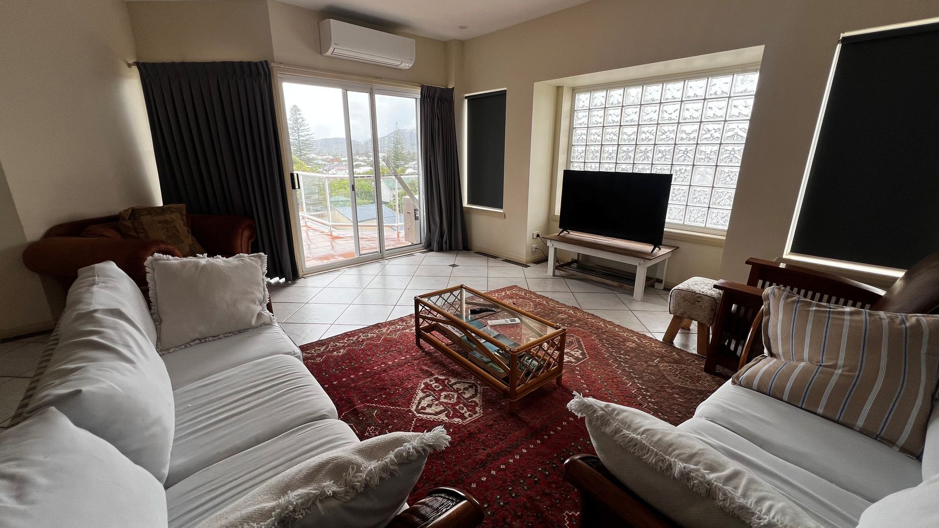 A living room with a sofa set, a coffee table, a television, and a view through the window.