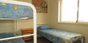 A bunk bed room with a window, a small wooden nightstand, and a colorful abstract painting on the wall. - SEABREEZE APARTMENTS UNIT 4 - AIRCONDITIONED CENTRE OF TOWN (South West Rocks)