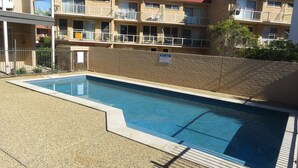 Una piscina rectangular con borde de azulejos, rodeada por una superficie de grava.