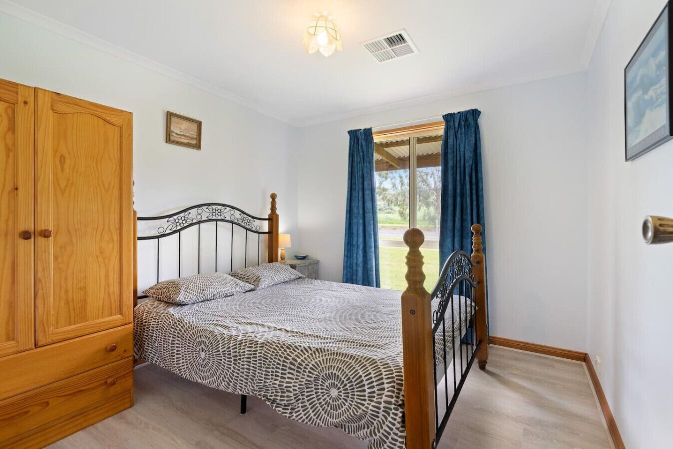 A bedroom with a bed, wooden wardrobe, and a window with curtains.