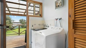 Un lavadero con lavadora, un lavabo y una ventana con vistas a una terraza.