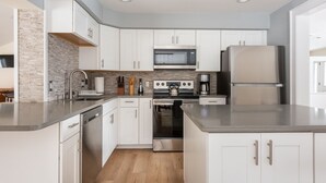 A modern kitchen with white cabinets, a stainless steel refrigerator, and a built-in oven. - Ski Mountain Chalet w/ Hot tub, Fireplace, Game Room -Windham Mountain (Hensonville)