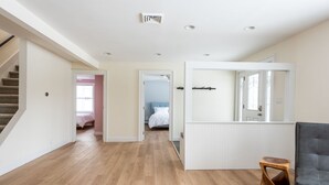 A spacious hallway with wooden flooring, a staircase, and a bed in the background. - Ski Mountain Chalet w/ Hot tub, Fireplace, Game Room -Windham Mountain (Hensonville)