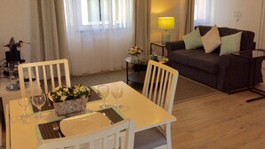 Un coin repas avec une table dressée pour deux personnes, un canapé et une lampe.