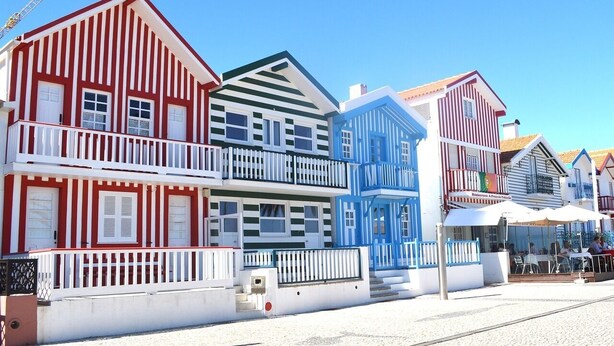 A row of colorful buildings with balconies, a restaurant, and outdoor seating. - HC Torreira Beach (Torreira Aveiro)