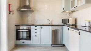 A modern kitchen with a built-in oven, dishwasher, and microwave. - HC Torreira Beach (Torreira Aveiro)