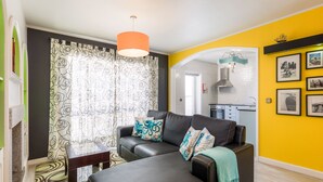 A modern living room with a sofa, ottoman, and a dining area visible through an archway. - HC Torreira Beach (Torreira Aveiro)