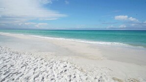 A beach with white sand and clear turquoise water.