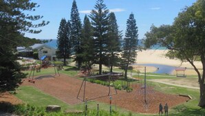 A golf course with a clubhouse, a sandy beach, and a clear blue sky.