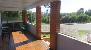 A covered outdoor area with wooden flooring, brick pillars, and a white fence. - MRS MOTTEES COTTAGE - SHORT STROLL TO BEACH, AIRCONDITIONED & PET FRIENDLY. (South West Rocks)